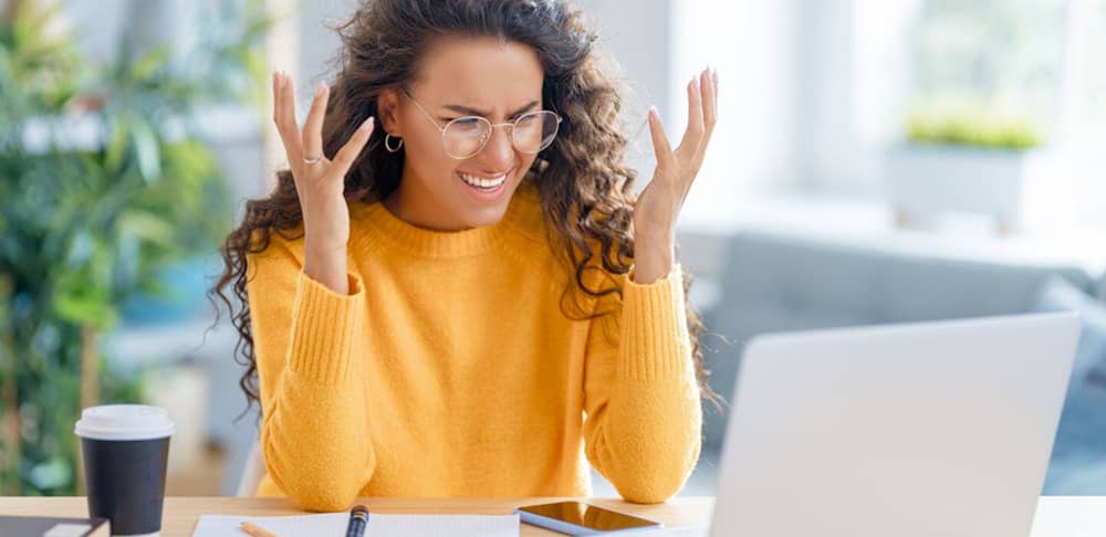 Eine Frau die vor dem Monitor die Hände in die Luft hält